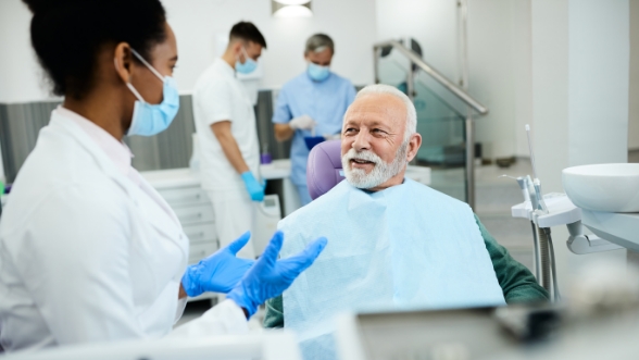 Senior man in dental chair talking to dentist