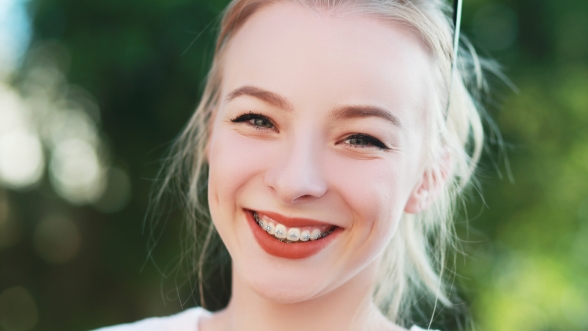 Girl with traditional braces smiling outdoors